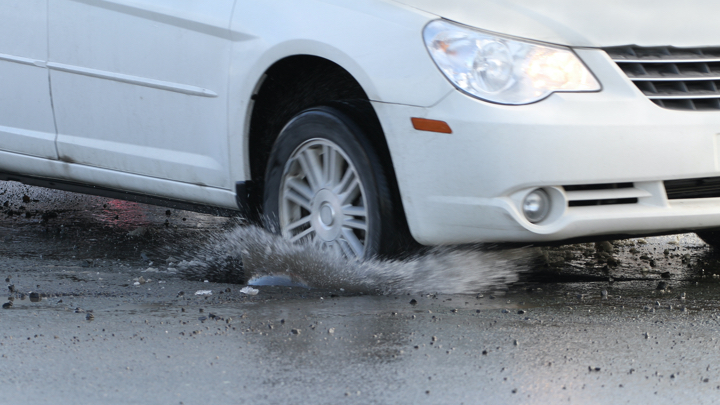 Car driving over pothole.